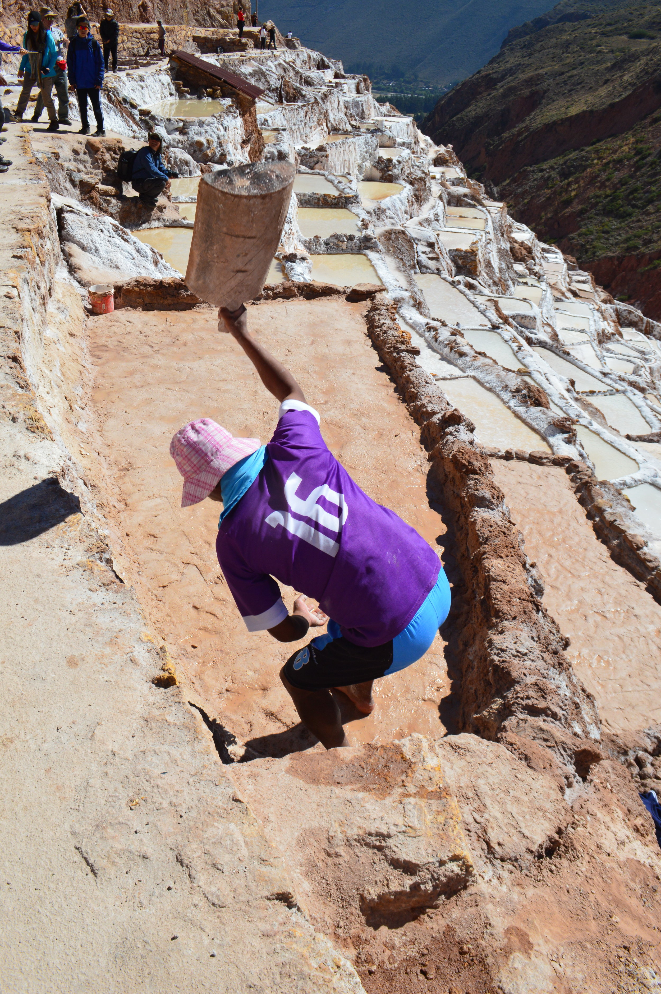 Worker using wooden baton to flatten the ground of the pond